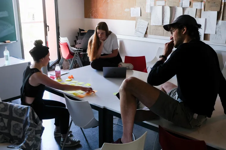 Three students working through sticky notes around a studio table in Barcelona.